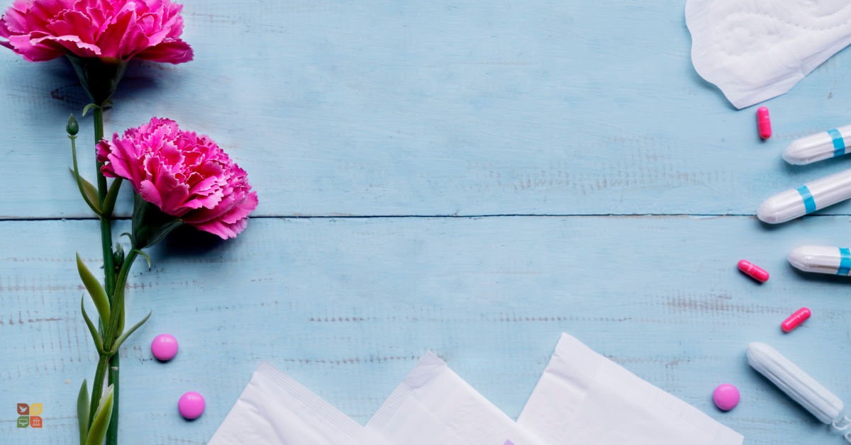 Flat lay of menstrual pads, pills, and pink flowers on a light blue background, representing women’s health and menstrual care.